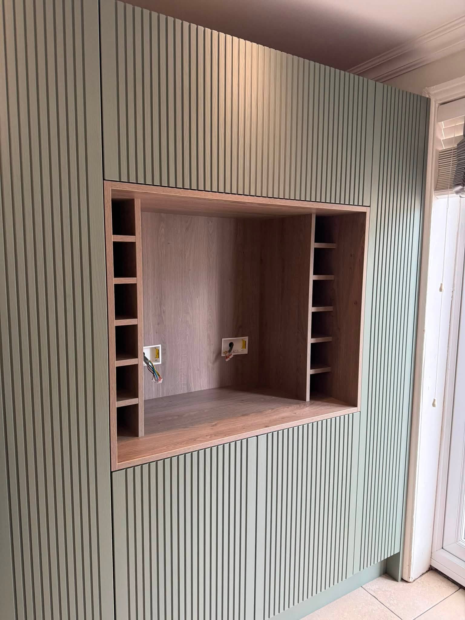 Fitted media wall with TV recess and wine rack shelving, installed by Interiors by Build NE in Gosforth