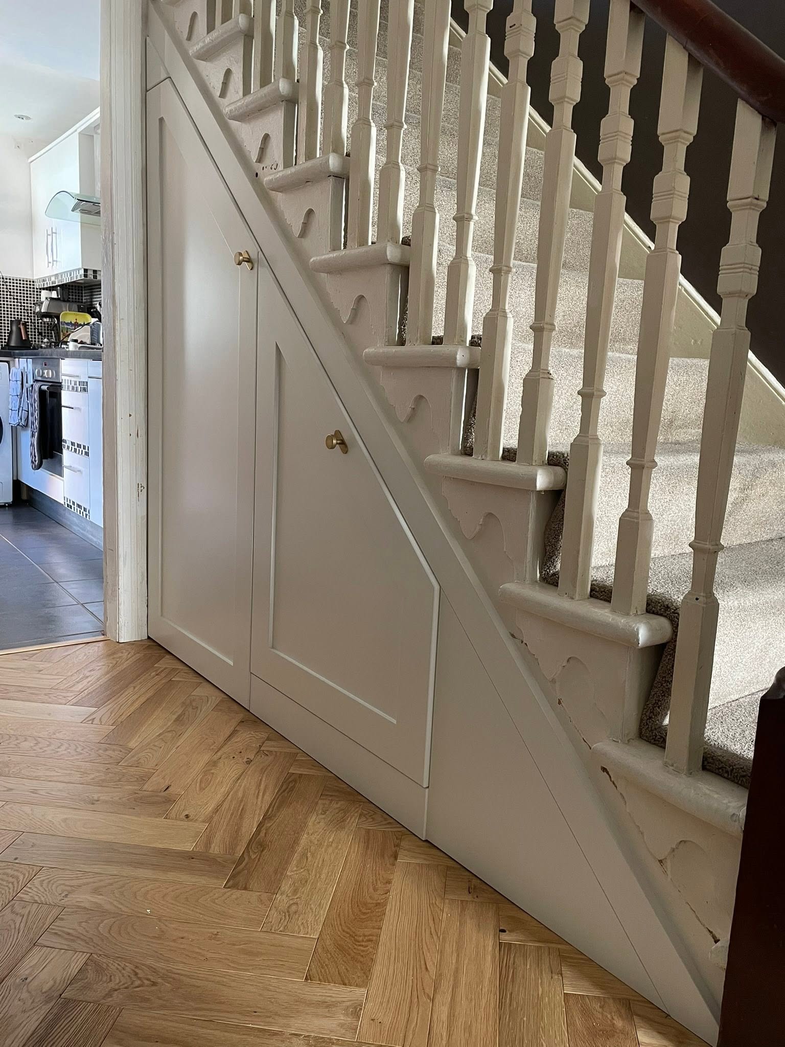 Bespoke under-stairs storage cupboards with herringbone flooring, installed by Interiors by Build NE in Cramlington